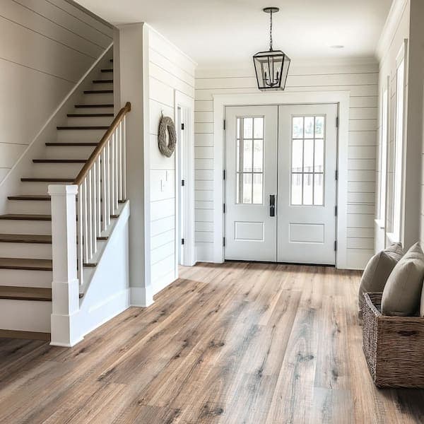 Bright modern farmhouse foyer with white shiplap walls, light wood floors, and a wooden staircase.